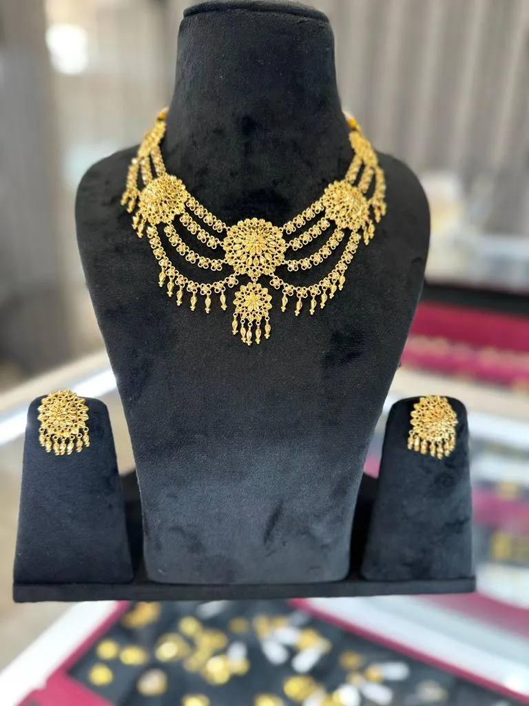 Gold kundan-style necklace and earring set displayed on a velvet bust