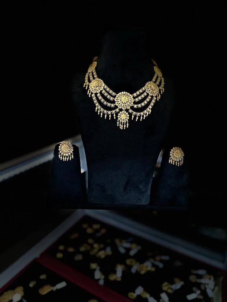 Gold necklace and earring set in dramatic studio lighting